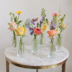 five vases with flowers are sitting on a marble table