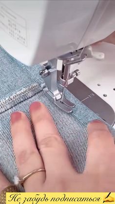 someone is using a sewing machine to sew on some blue jean pants with their fingers