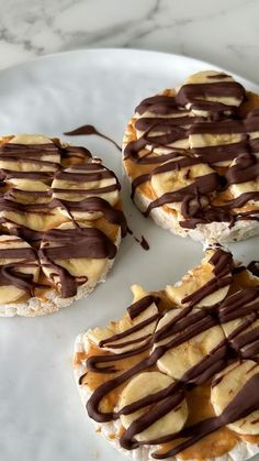 four desserts on a plate with chocolate drizzled on them