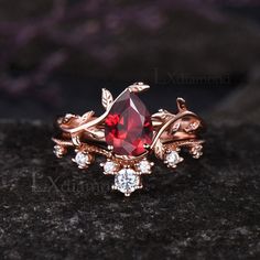 a close up view of a ring with a red stone and white diamonds on it