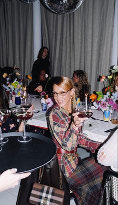 a woman sitting at a table holding a wine glass