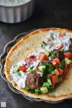a pita with meatballs and vegetables on it
