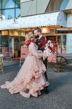 a man and woman standing in front of a store with flowers on their wedding day