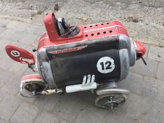 an old red motor scooter with number 12 on the front and side wheel