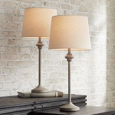 two lamps sitting on top of a table next to a brick wall