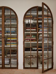two arched glass doors with bookshelves in the middle and shelves full of books behind them