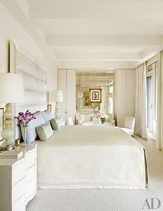 a large white bed sitting in a bedroom next to two lamps on either side of it