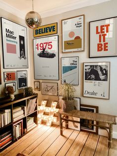 a room filled with lots of posters on the wall next to a wooden table and bookshelf