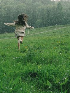a girl running in the rain with her arms outstretched