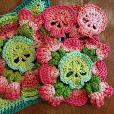two crocheted flowers on top of a wooden table next to a green pot holder
