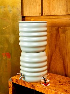 a large white vase sitting on top of a wooden table next to a wall with wood paneling