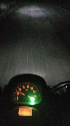 the dashboard of a motorcycle at night with its lights on and speedometer illuminated up