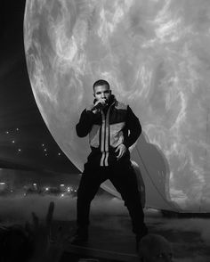 a man standing on top of a stage next to a giant object in the air