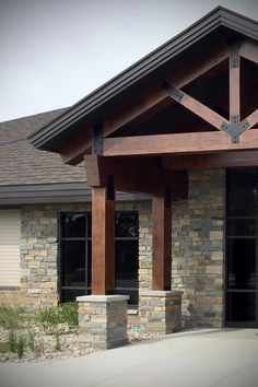 an outside view of a house with stone pillars and wood beams on the front porch