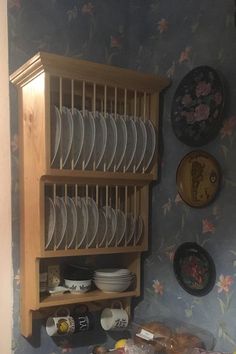 a wooden shelf filled with lots of plates next to a wall mounted dishwasher