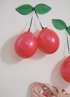 two cherries hanging from the side of a wall