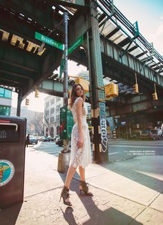 a woman is walking down the sidewalk near a street sign