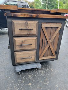 a wooden cabinet sitting in the middle of a parking lot next to a truck and trees