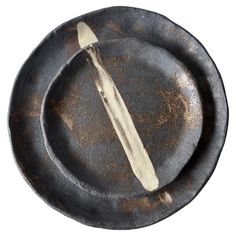an old black plate with a wooden spoon on it and a dirty fork in the middle