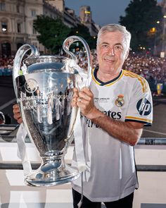 an older man holding up a soccer trophy