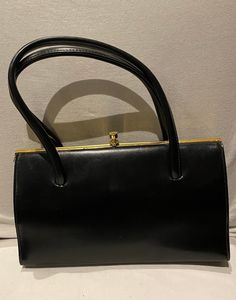 Here is a beautiful black FREEDEX vintage 1940s -50s ladies double top handle handbag / purse. This beautiful handbag has a gold coloured metal frame. Also is lined in black fabric with 1 pocket, this is a beautiful vintage FREEDEX handbag.  A great vintage piece for All you great vintage lovers  Label :   FREEDEX  Measurements :   Approximately  Height :  6 -  Inches  Length :  10 - 3  -  Inches  Condition :   Good vintage condition  Couple of scratches over the handbag, gold coloured metal sli Top Handle Bags, 1940s Bags Handbags, 1950 Handbags, 1940s Handbags, 50s Ladies, Handbag Gold, Goodwood Revival, Vintage Lovers, Black Handbag