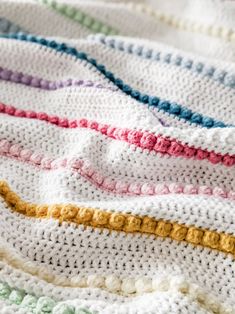 a crocheted blanket with multicolored stripes on it's edges and bottom