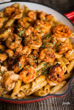 pasta with shrimp and parsley in a skillet on a wooden table, ready to be eaten