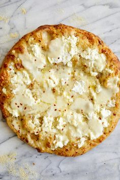 a close up of a pizza with cheese on it sitting on a marble counter top