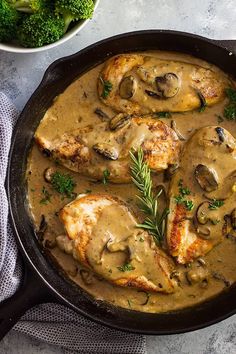 chicken with mushroom gravy in a skillet next to broccoli