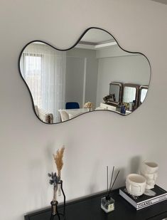 a mirror that is sitting on top of a dresser next to a vase with flowers