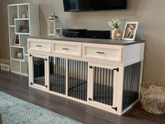 a tv mounted on the wall above a dog kennel in a living room with hardwood floors