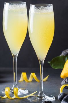 two champagne flutes with lemon peels next to them