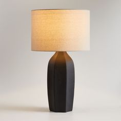 a black table lamp with a white shade on it's base and a beige linen lampshade