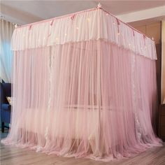 a pink canopy bed with fairy lights on it