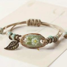 a close up of a bracelet with beads and flowers on it's end, sitting on a piece of paper