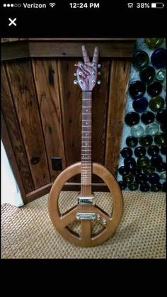 a wooden guitar with a peace sign on it's neck and hands in the middle