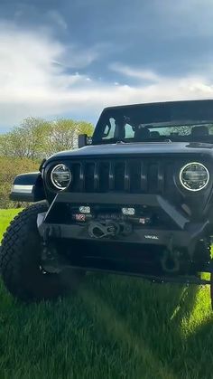 a black jeep parked in the grass with its hood up and front bumpers down