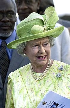 an older woman wearing a green hat and holding a book in front of other people