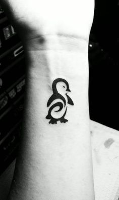 a small penguin tattoo on the wrist is shown in this black and white photo,