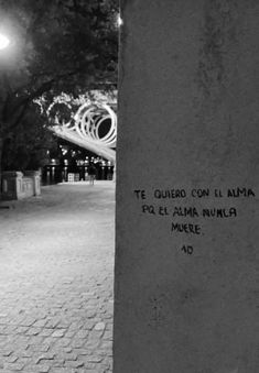 a black and white photo with writing on the side of a pillar in front of a street light