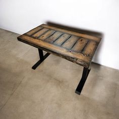 a wooden table sitting on top of a floor next to a white wall and cement floor