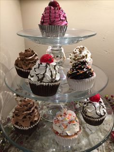 a three tiered glass plate with cupcakes on it