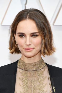 a woman with short hair wearing a black suit and gold necklace on the red carpet