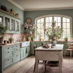 a kitchen filled with lots of green cabinets and flowers in vases on top of a wooden table