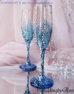 two blue wine glasses sitting next to each other on top of a white table cloth