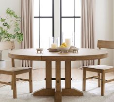 a dining table with two chairs and a bowl of fruit on it in front of a window