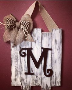 a wooden sign with the letter m on it and a burlocked bow