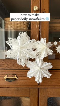 some paper snowflakes hanging from a wooden door frame with the words how to make paper doily snowflakes