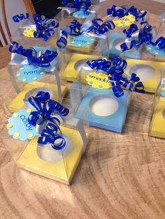 six boxes with blue bows on them sitting on a table top, ready to be used as favors