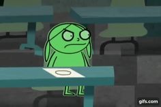 a green cartoon character sitting at a table